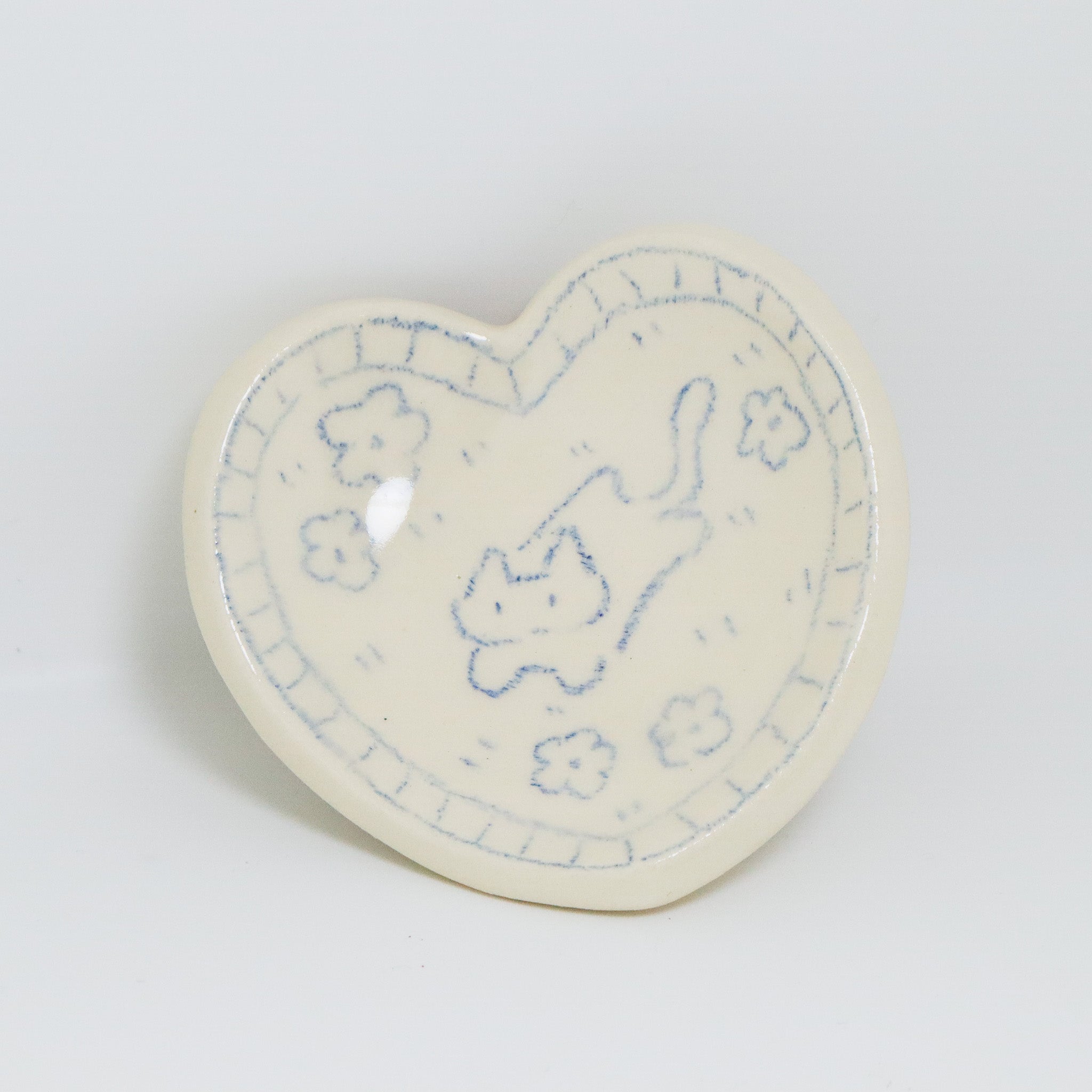 Heart-shaped ceramic plate with blue cat design on a light gray background