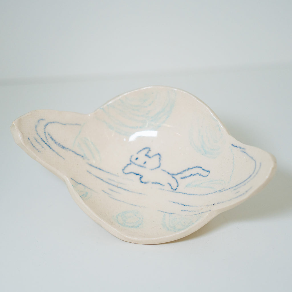 Ceramic dish in the shape of a planet with blue abstract design on a light gray background