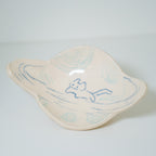 Ceramic dish in the shape of a planet with blue abstract design on a light gray background