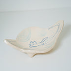 Ceramic planet-shaped dish with blue detailing on a light gray background