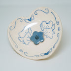 Heart-shaped ceramic plate with blue floral design on a light gray background