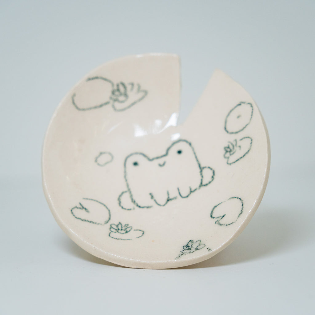 Ceramic plate with frog design on a light gray background