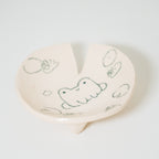 Heart-shaped ceramic plate with hand-drawn designs on a white background