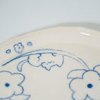 Ceramic plate with blue floral patterns and a cat drawing on a white background