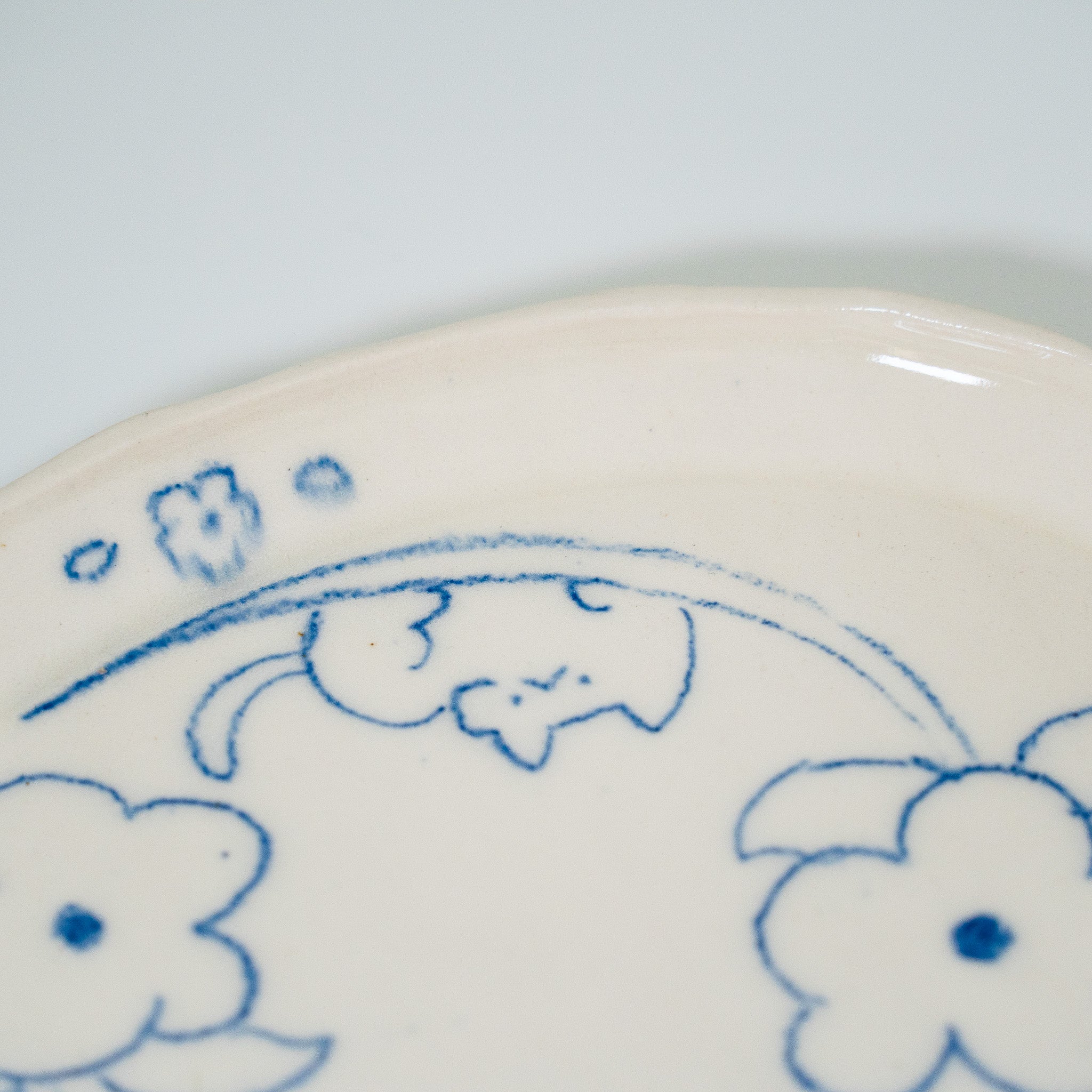 Ceramic plate with blue floral patterns and a cat drawing on a white background
