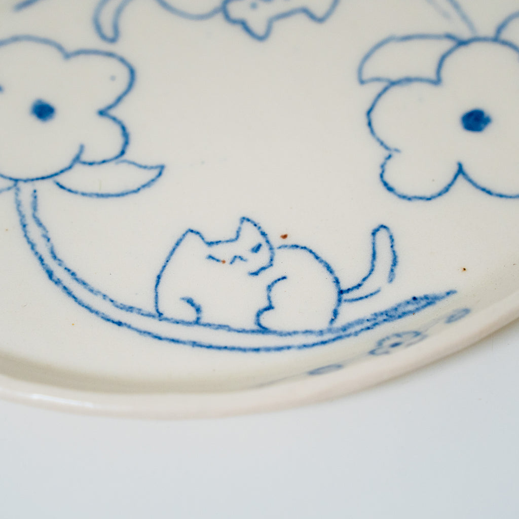 Ceramic plate with blue floral and cat design on a white background