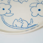 Ceramic plate with blue floral and cat design on a white background