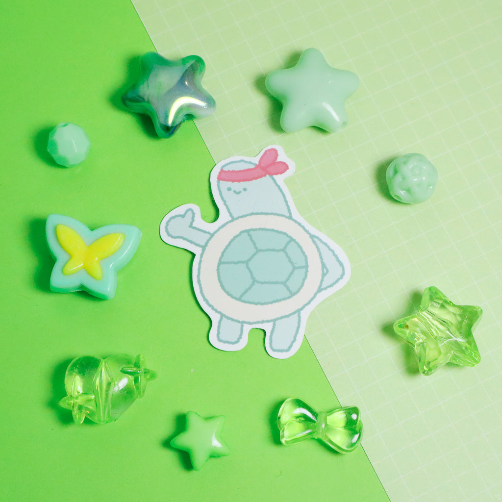 Cartoon turtle sticker surrounded by star-shaped objects on a green background