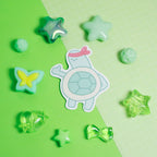 Cartoon turtle sticker surrounded by star-shaped objects on a green background