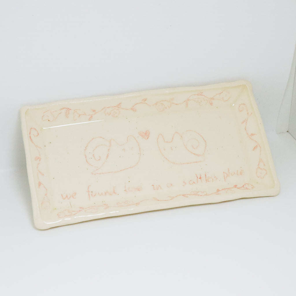 Rectangular ceramic plate with decorative designs and text on a white background