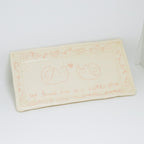 Rectangular ceramic plate with decorative designs and text on a white background