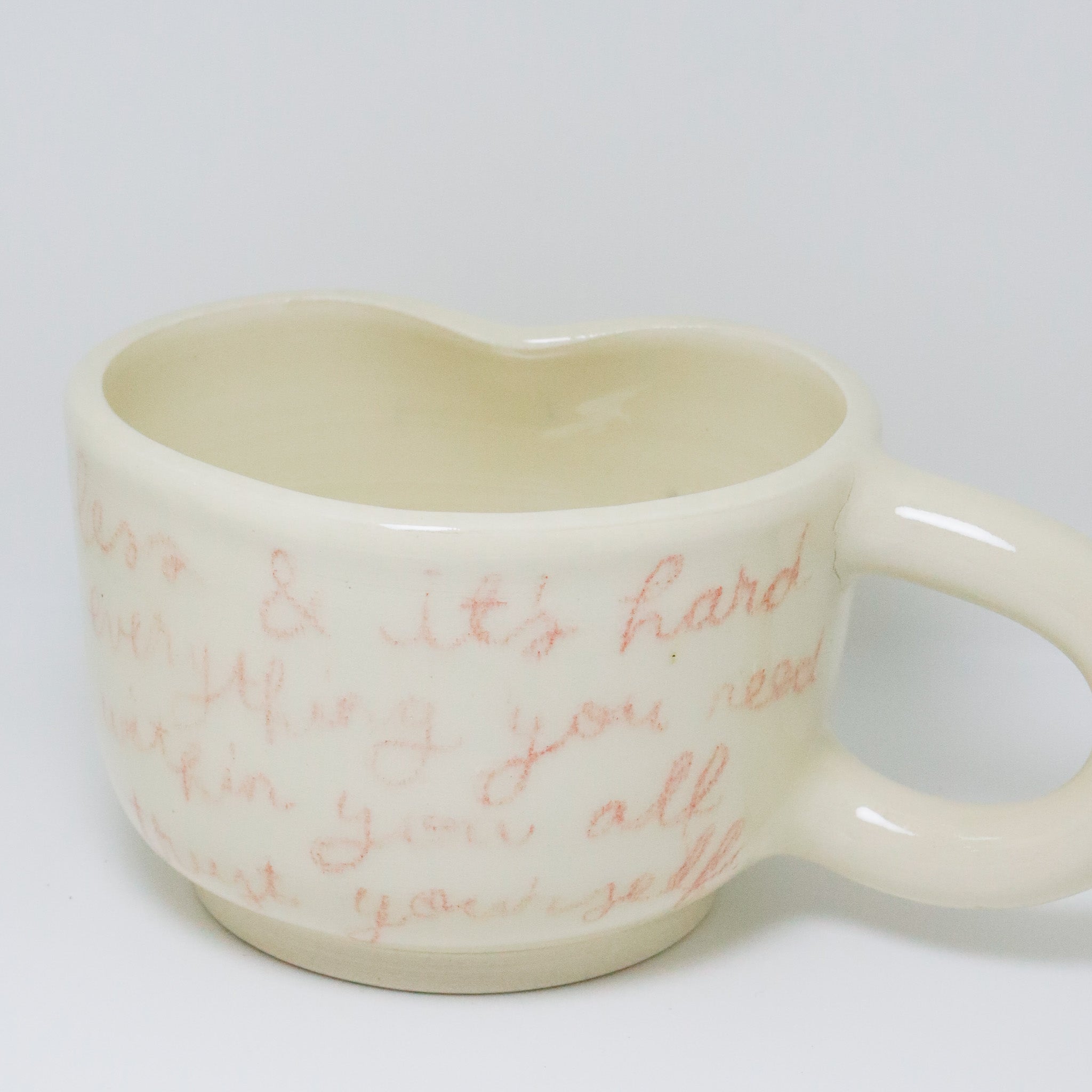Heart-shaped mug with red text on a white background