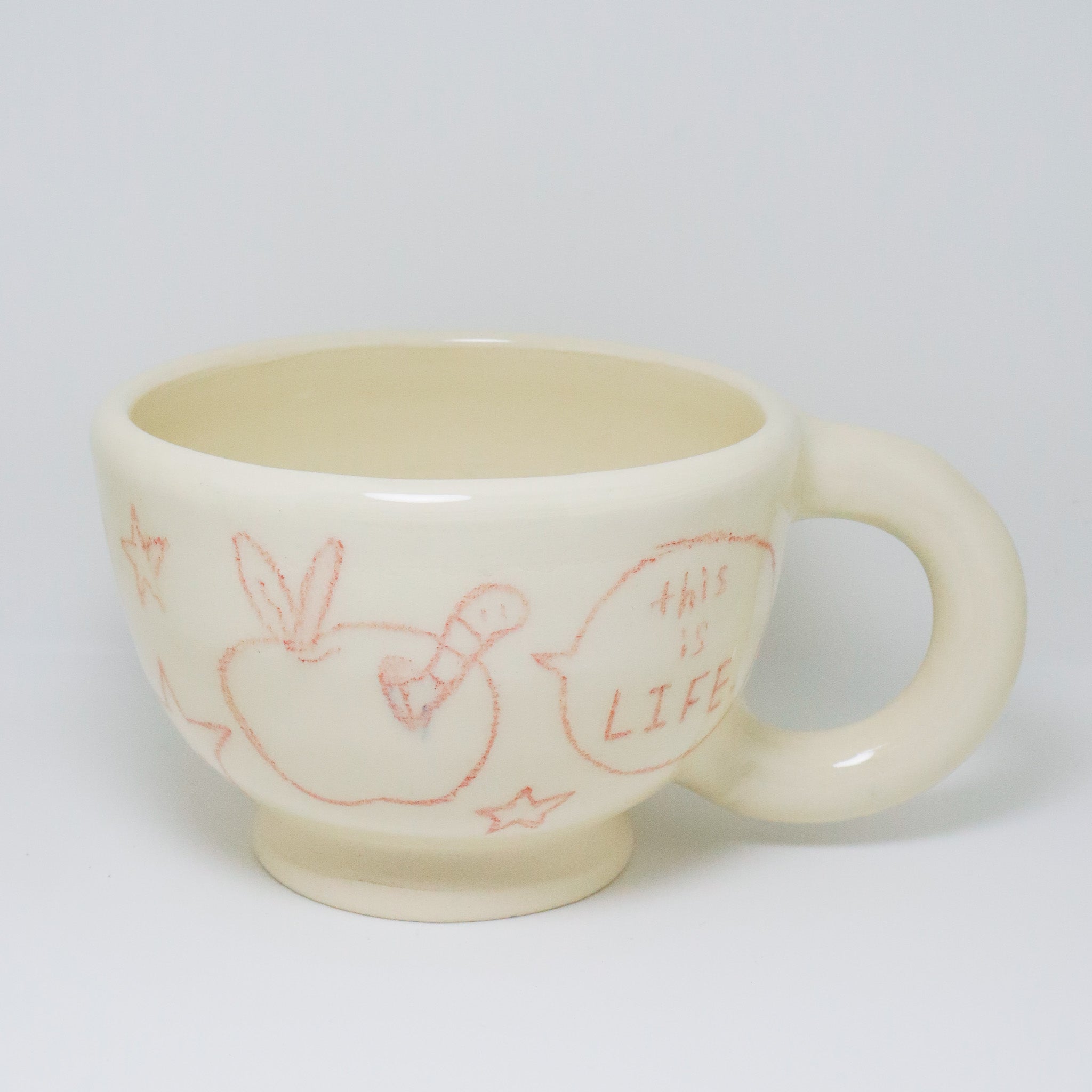 White ceramic mug with red illustrations and text on a white background