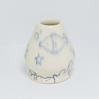 A matcha whisk holder with blue illustrated designs on a white background