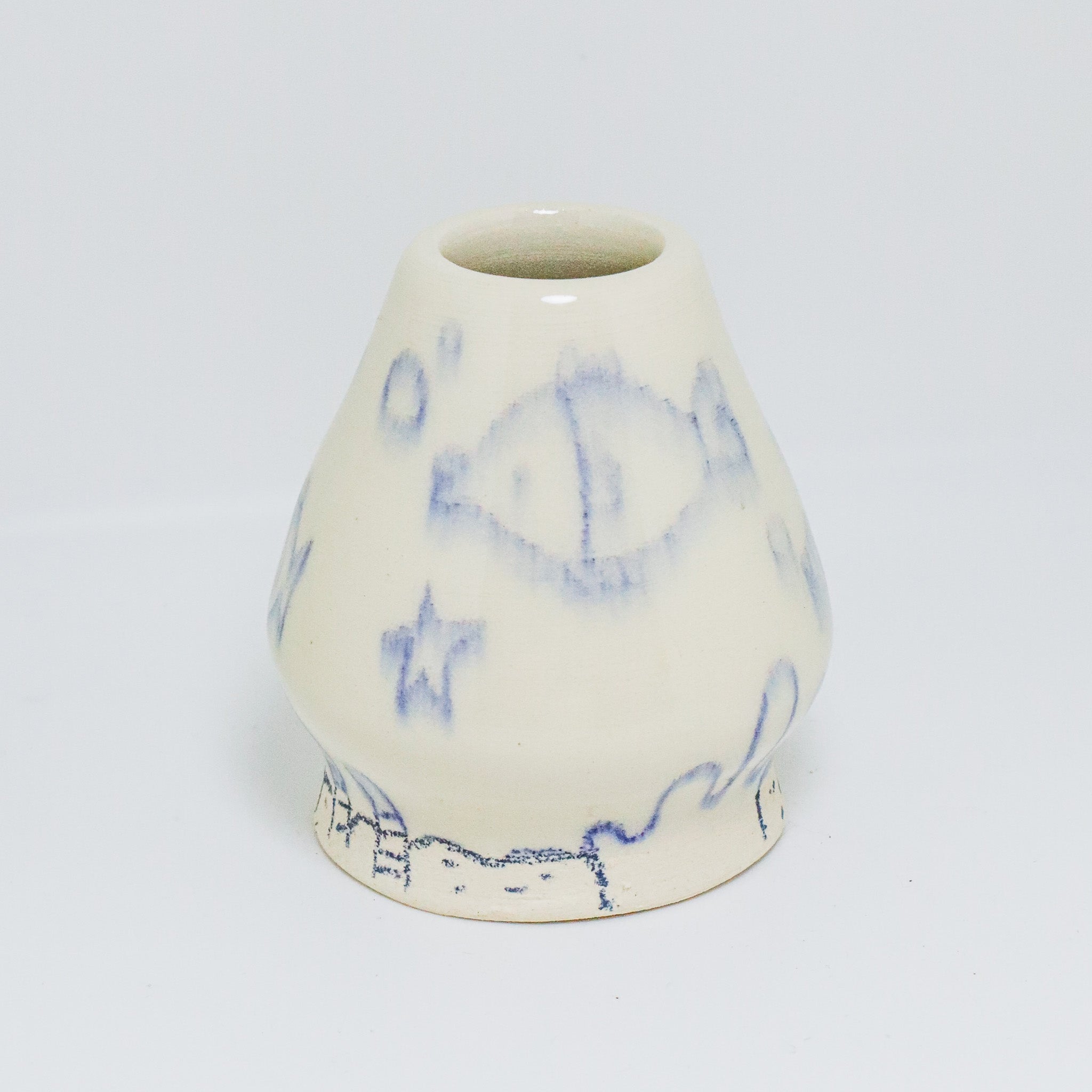 A matcha whisk holder with blue illustrated designs on a white background