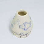 A matcha whisk holder with blue illustrated designs on a white background