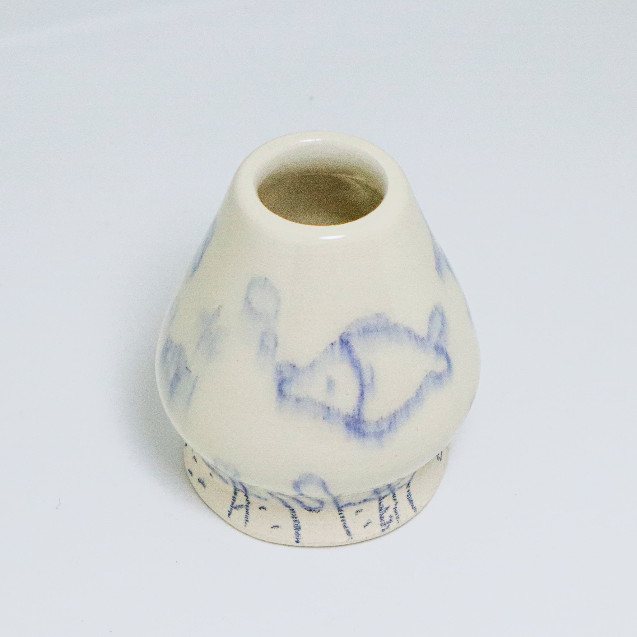 A matcha whisk holder with blue illustrated designs on a white background