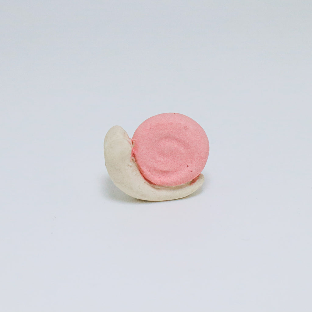 Pink and white ceramic snail on a light gray background