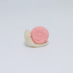 Pink and white ceramic snail on a light gray background