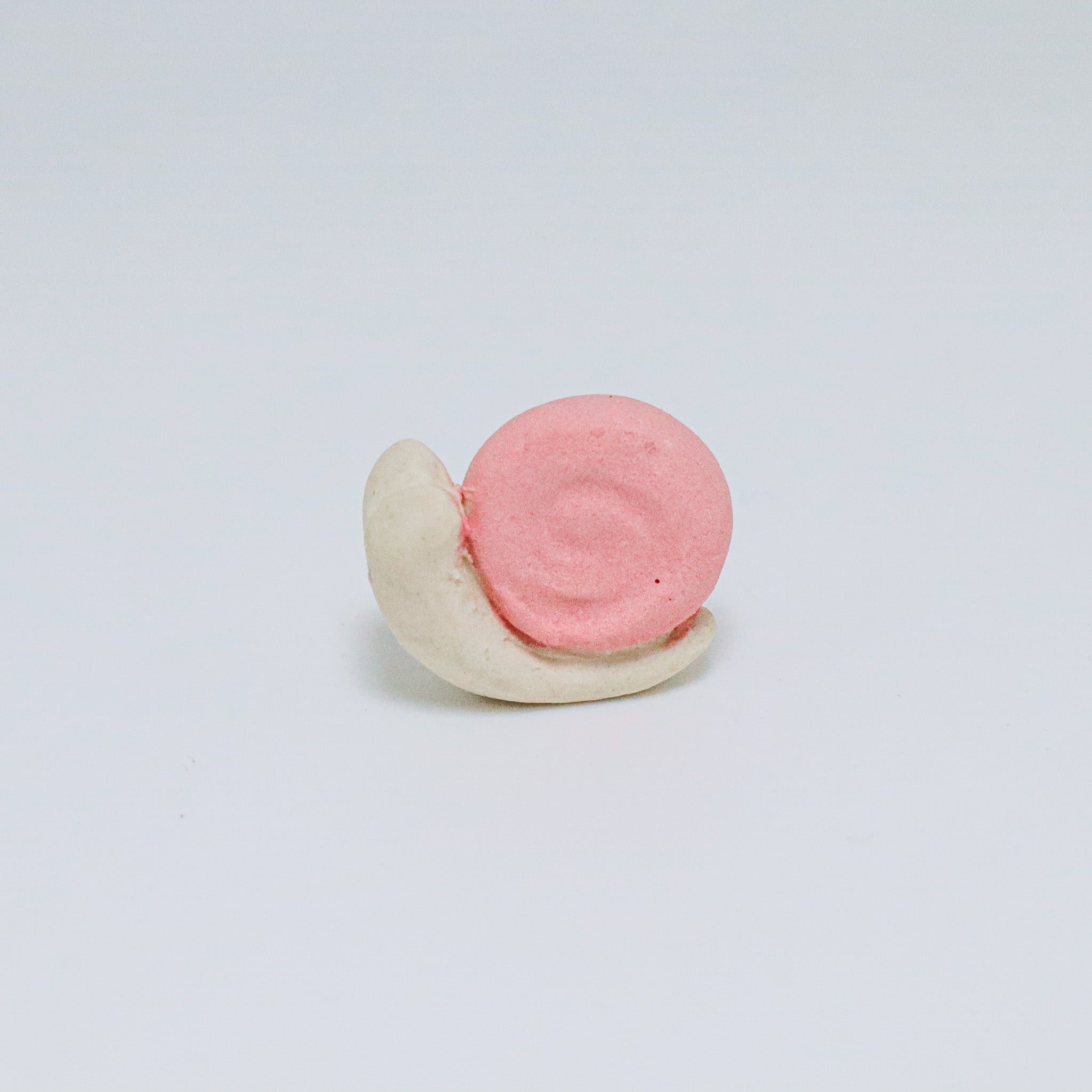 Pink and white ceramic snail on a light gray background