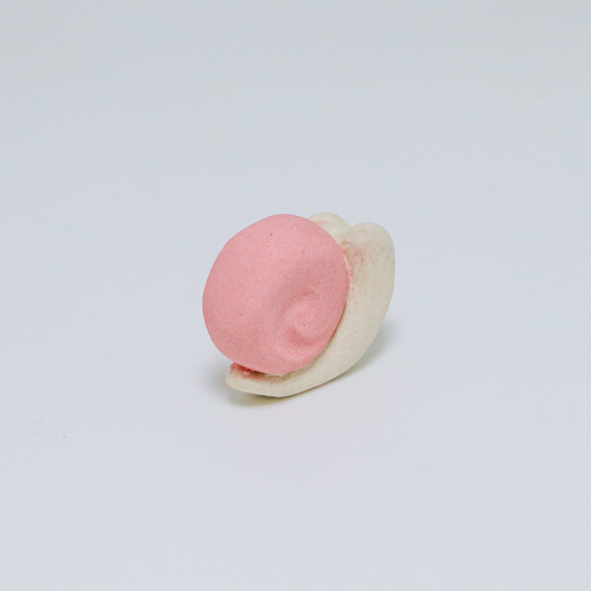 Pink and white ceramic snail on a light gray background