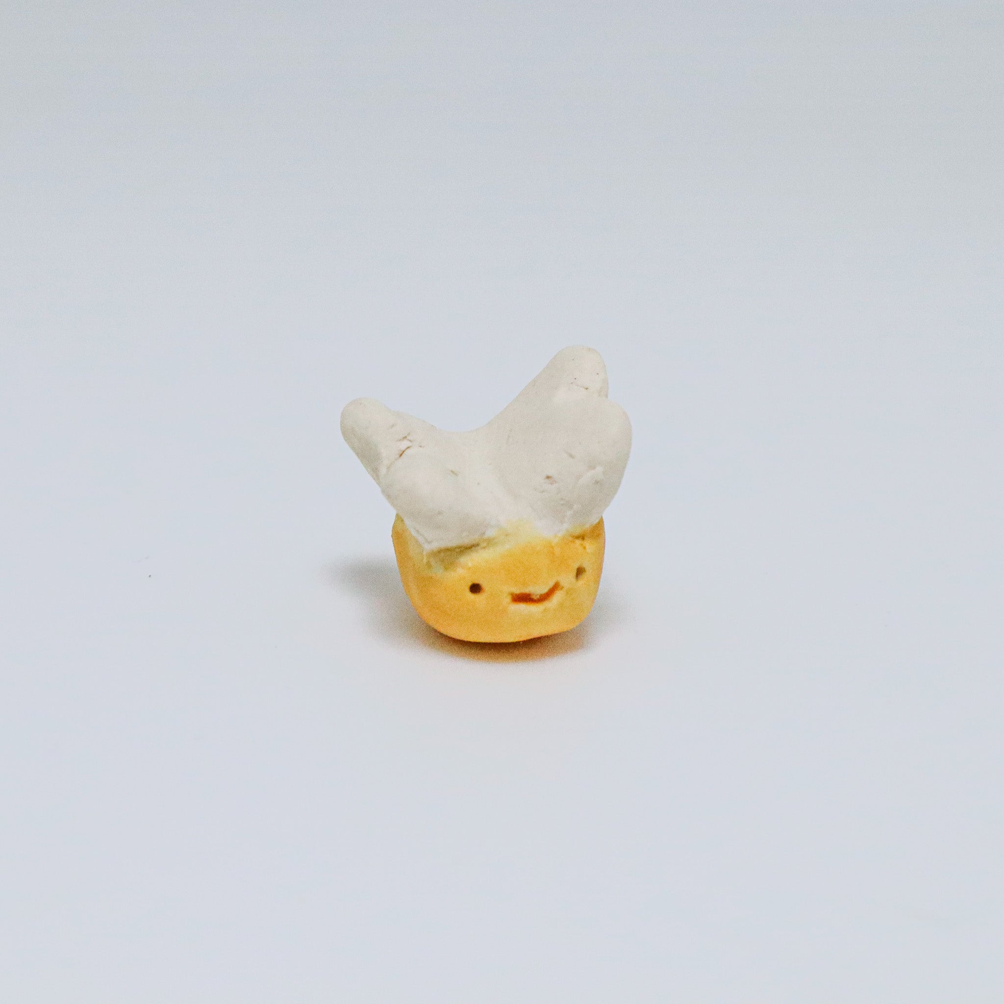 Small figurine of a bee with a smiley face on a light gray background