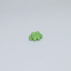 Small green frog ceramic figurine on a light gray background