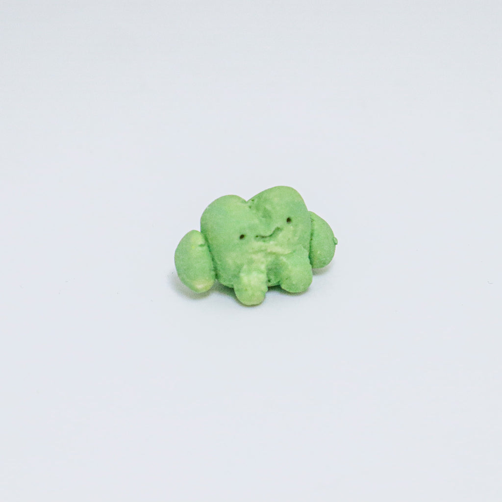 Green ceramic frog on a light gray background