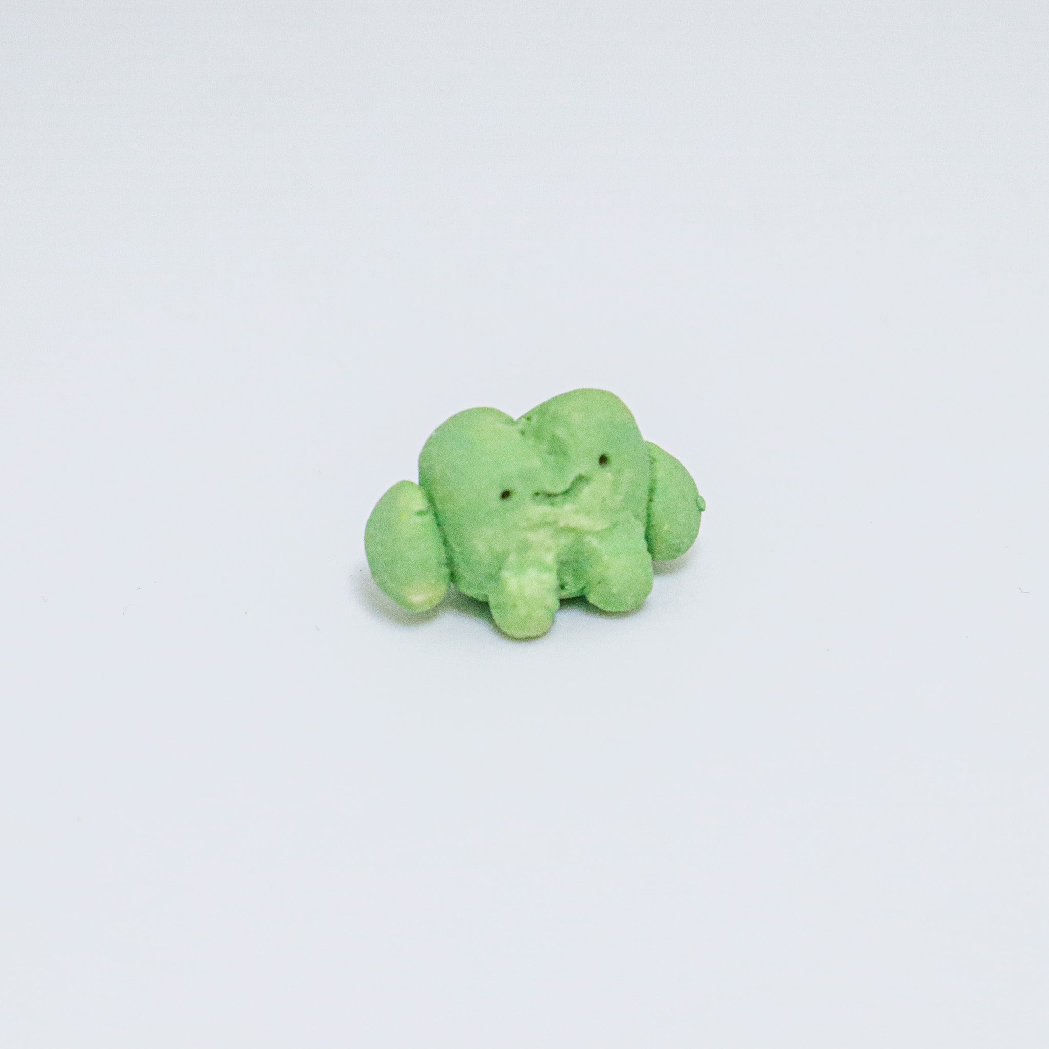 Green ceramic frog on a light gray background